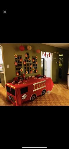 a firetruck themed birthday party with red table cloths and paper lanterns hanging from the ceiling