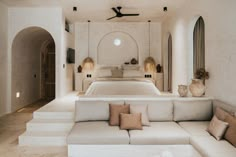 a large white couch sitting next to a bed in a bedroom under a ceiling fan