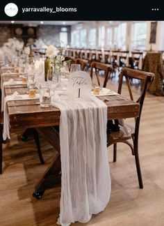 the table is set up with white linens and place settings for guests to sit at