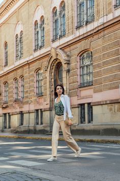 a woman crossing the street in front of an old building