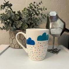 a coffee cup sitting on top of a table next to a potted plant