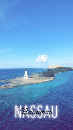 an island with a light house on it in the middle of the ocean, surrounded by blue water