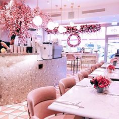 the interior of a restaurant with pink chairs and flowers on the counter, in front of an ice cream parlor