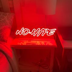 a red neon sign that says hope on top of a night stand next to a bed