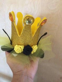 a hand holding up a gold crown with flowers on it