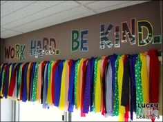 colorful ribbons are hanging on the wall in front of a sign that says work hard, be kindle