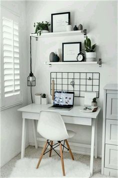 a white desk with a laptop computer on top of it next to a shelf filled with potted plants