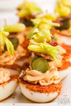 deviled eggs topped with pickles and other toppings