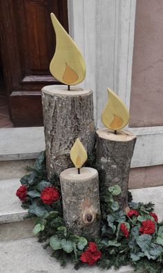 three wooden logs with candles on them sitting in front of a door and wreaths