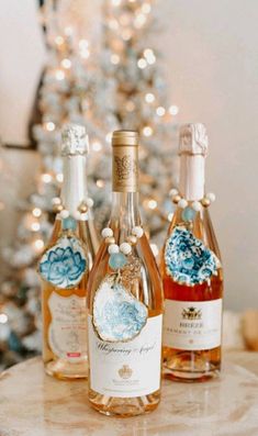 three bottles of wine sitting on top of a table next to a small christmas tree