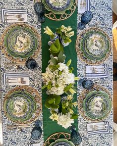 the table is set with plates, flowers and napkins in blue and green colors