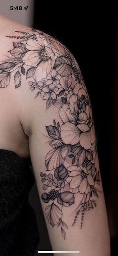 a woman's arm with flowers and leaves tattooed on the side of her shoulder