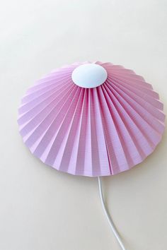 a pink fan sitting on top of a white table next to a light bulb in the shape of a flower