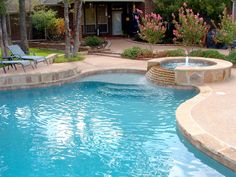 a small pool with a waterfall in the middle and chairs around it on either side