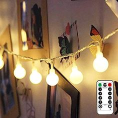 a string of light bulbs hanging from a wall next to a remote control and pictures on the wall