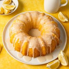 a lemon bunt cake with icing on a plate next to sliced lemons