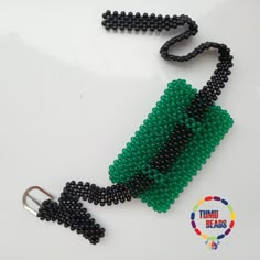 a green and black beaded keychain on a white surface