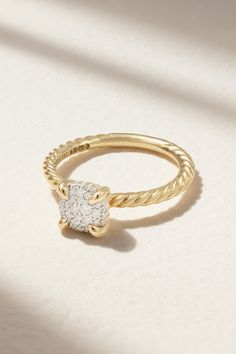 a yellow gold ring with a diamond set in the center, sitting on a white surface