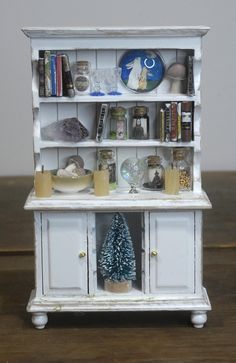 a white book shelf with books and other items on it, sitting on top of a wooden table