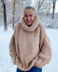 an older woman standing in the snow wearing a sweater