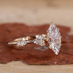 a close up of a diamond ring on top of a brown leaf with leaves in the background