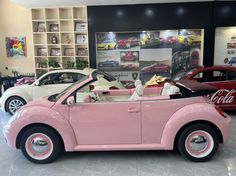 a pink car parked inside of a building next to other cars