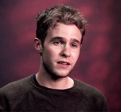 a man in a black shirt is looking at the camera with a serious look on his face