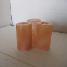 three orange candles sitting on top of a white surface