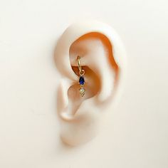 an ear is shown with a blue and yellow stone in the top part of it