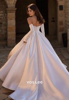 a woman in a white wedding dress standing on a stone walkway with her back to the camera