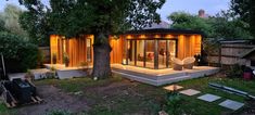 a small house is lit up at night in the back yard, with lights on