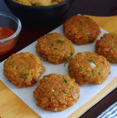 six crab cakes on a cutting board next to a bowl of dipping sauce and chips