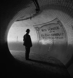 a man standing in the middle of a tunnel with his back turned to the camera