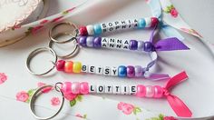 three personalized keychains with name tags on them sitting next to a ribbon