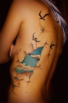 the back of a woman's body with birds flying over it