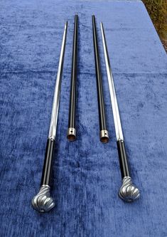 two silver and black pool cues laying on a blue table cloth next to each other