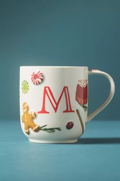 a coffee cup with the letter m painted on it's side and candy canes