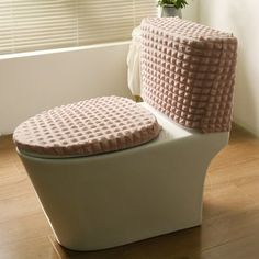 a white toilet sitting on top of a hard wood floor next to a potted plant