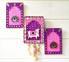 two pink and purple wall hangings with tassels on the sides, one in the shape of a cow