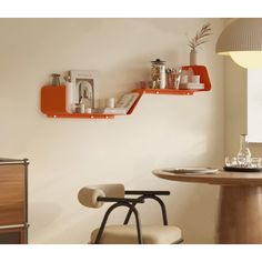 two orange shelves on the wall above a dining room table