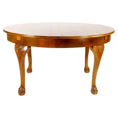 an oval wooden table with carved legs and a white marble top, against a white background