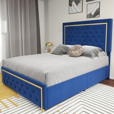 a bed with blue upholstered headboard and foot board in a white room