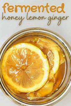 a glass jar filled with honey lemon ginger syrup and sliced lemons on top of it