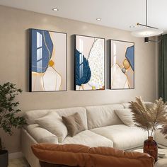 three paintings hang on the wall above a couch in a living room with a large window