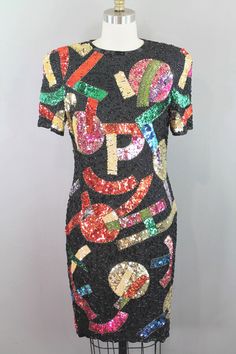 This 1980s-90s beaded cocktail dress is such a fun piece! An Oscar Creations original, this little dress has a unique abstract pattern with letters of the alphabet incorporated throughout. This style has made its way back around...Kelly Clarkson would agree!  Measurements:  *Marked Size 8 Bust- 36in Waist- 32in Hip- 36in Sleeve- 10in Shoulder to Hem- 37in Purveyor's Note: We have searched far and wide, wrestled bears, braved the cold, traversed mountain ranges, fought pirates, swam with sharks and eaten at many a questionable road side taco stand to provide our customers with one of a kind vintage pieces.  Know that whichever piece you choose to make your own has its own story and has traveled through time to get to you.  Though we strive to provide the absolute best, "pristine" vintage pi Luxury Multicolor Sequin Cocktail Dress, Festive Multicolor Embroidered Sequin Dress, Vintage Embellished Sequin Summer Dress, Vintage Fitted Sequin Embellished Dress, Embellished Multicolor Sequin Mini Dress, Beaded Cocktail Dress, Kelly Clarkson, Little Dresses, Abstract Pattern