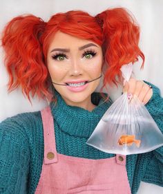 a woman with red hair and green eyes holding a plastic bag filled with fish in it