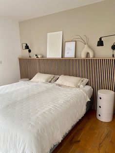 a white bed sitting in a bedroom next to a wooden headboard and two lamps