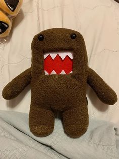 a stuffed animal with an open mouth and sharp teeth on it's chest sitting on a bed