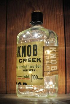 a bottle of knob creek whiskey sitting on top of a wooden table next to a wall