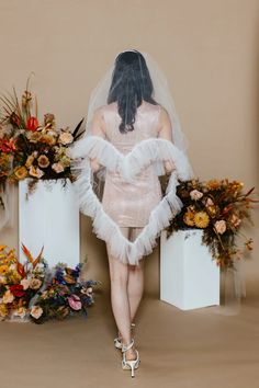 a woman in a wedding dress standing next to flowers